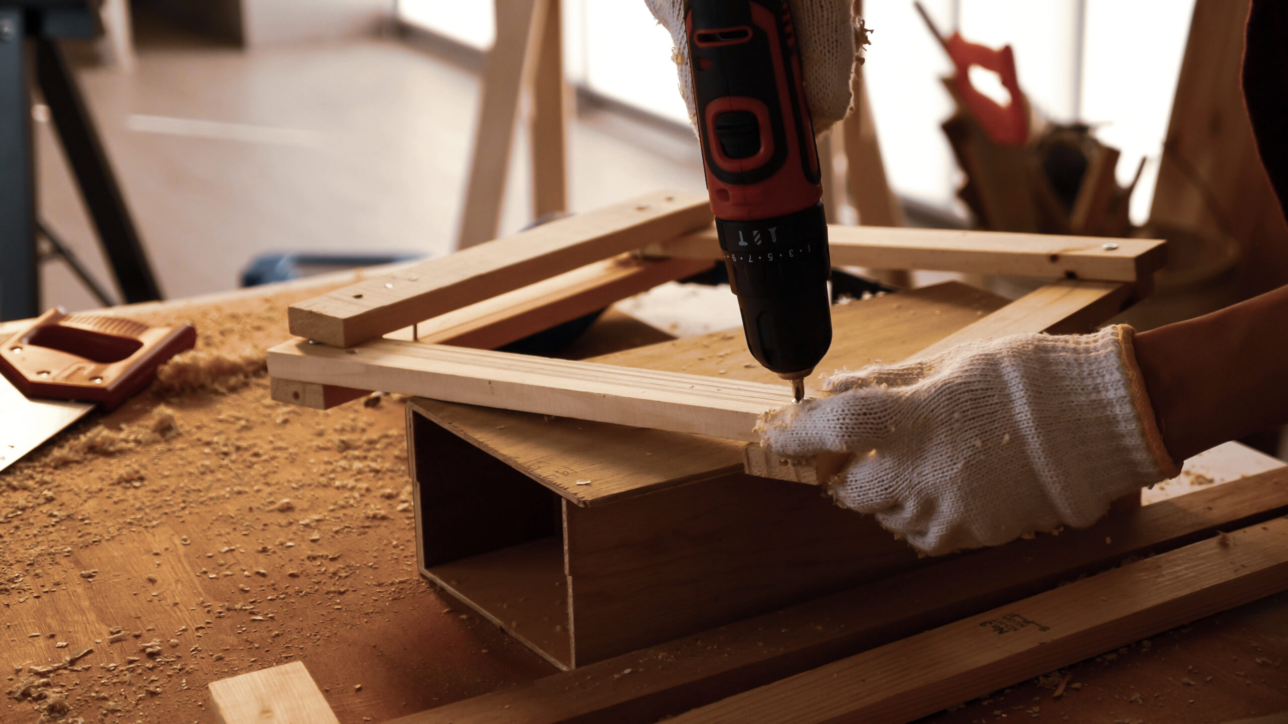 Carpenter using drill to screwing pieces of board at site.